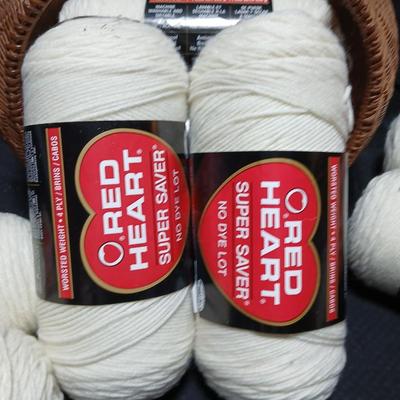 8 skeins of Red Heart Super saver yarn with a basket and knitting needles