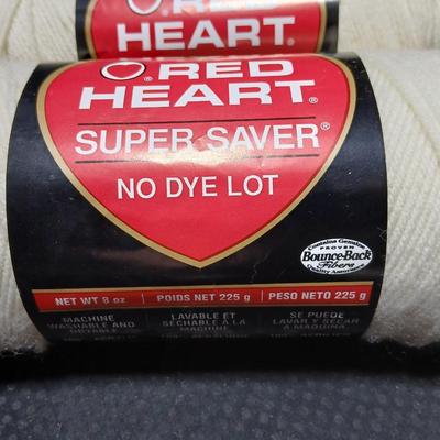 8 skeins of Red Heart Super saver yarn with a basket and knitting needles