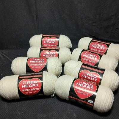 8 skeins of Red Heart Super saver yarn with a basket and knitting needles