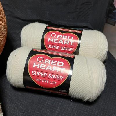 8 skeins of Red Heart Super saver yarn with a basket and knitting needles