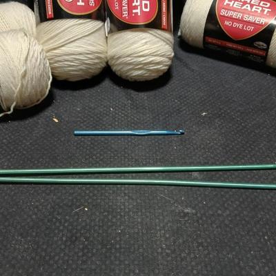 8 skeins of Red Heart Super saver yarn with a basket and knitting needles