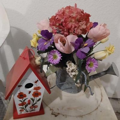 Two heavy duty plastic patio chairs, small table, galvanized watering can with flowers and a birdhouse