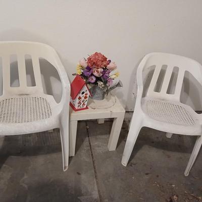 Two heavy duty plastic patio chairs, small table, galvanized watering can with flowers and a birdhouse