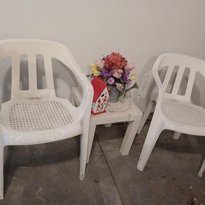 Two heavy duty plastic patio chairs, small table, galvanized watering can with flowers and a birdhouse