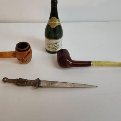 Two small tobacco pipes, champagne bubbles and a miniature metal dagger