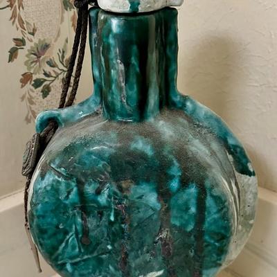 Teal pottery bottle with attached bolo