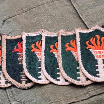 LOT 556: Army Jacket, Multiple Patches, Notice of Recruitment, Metal Pins, Cannon, & Charm, Postcard, & First Aid smelling Salts