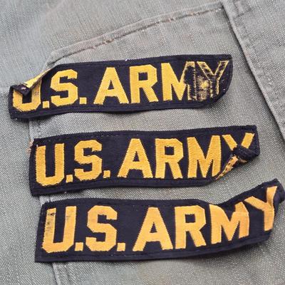 LOT 556: Army Jacket, Multiple Patches, Notice of Recruitment, Metal Pins, Cannon, & Charm, Postcard, & First Aid smelling Salts