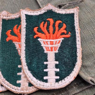 LOT 556: Army Jacket, Multiple Patches, Notice of Recruitment, Metal Pins, Cannon, & Charm, Postcard, & First Aid smelling Salts