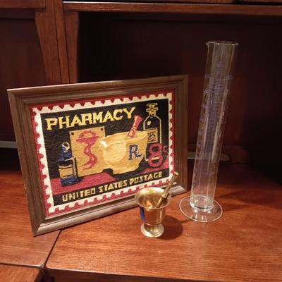 NEEDLEPOINT PHARMACY PICTURE, TALL GLASS BEEKER AND BRASS PESTLE & MORTAR