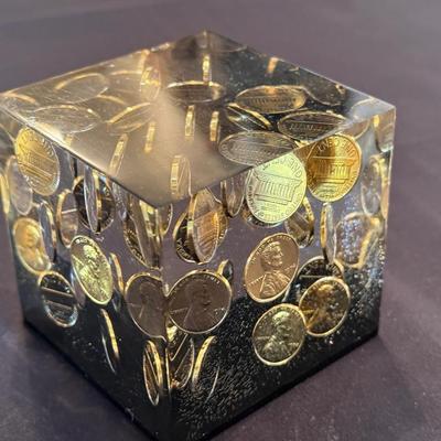 Acrylic cube with shiny pennies floating inside