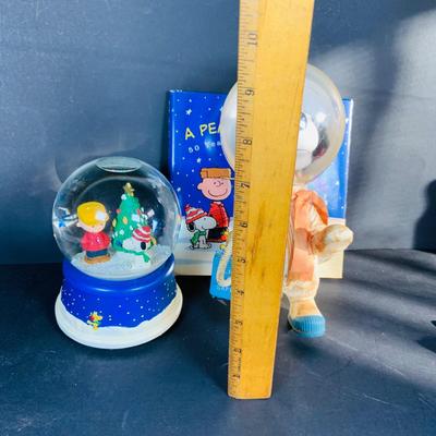LOT 134: Vintage Peanuts Snoopy Astronaut from 1969 and 50th Anniversary Peanut Holiday Book and Snow Globe