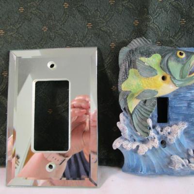 Light switch covers, one is mirrored, one has a fish