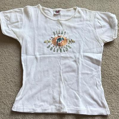 LOT 216A: NFL Team Merch: Green Bay Packers (Shirts, Jersey, Sweatpants), Miami Dolphins (Bedazzled Tee, Dan Marino Starter T, Jersey),...