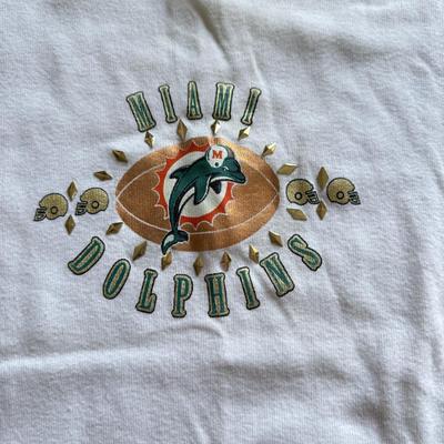 LOT 216A: NFL Team Merch: Green Bay Packers (Shirts, Jersey, Sweatpants), Miami Dolphins (Bedazzled Tee, Dan Marino Starter T, Jersey),...