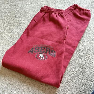 LOT 216A: NFL Team Merch: Green Bay Packers (Shirts, Jersey, Sweatpants), Miami Dolphins (Bedazzled Tee, Dan Marino Starter T, Jersey),...