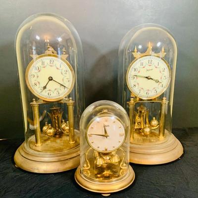 LOT 31: Set of Three (3) Mechanical Glass Dome Anniversary Clocks Featuring John Wanamaker, Forestville German Made Clock and a Smaller...