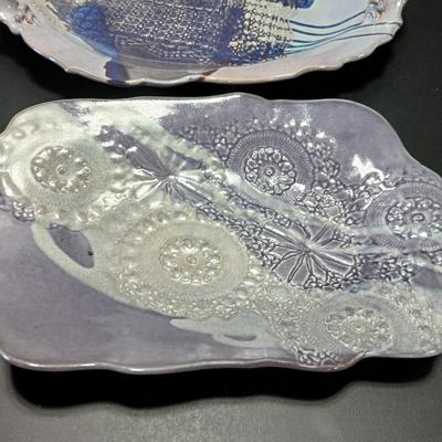 Two purple pottery dishes with signatures on the backs