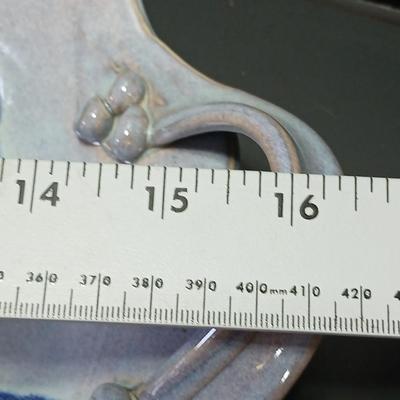 Two purple pottery dishes with signatures on the backs