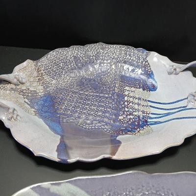 Two purple pottery dishes with signatures on the backs