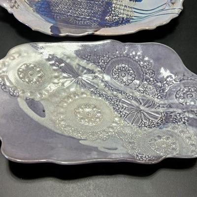 Two purple pottery dishes with signatures on the backs