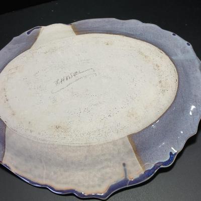 Two purple pottery dishes with signatures on the backs