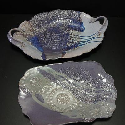 Two purple pottery dishes with signatures on the backs