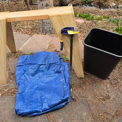 Wooden sawhorse, a blue tarp, Irwin clamp, and a trashcan