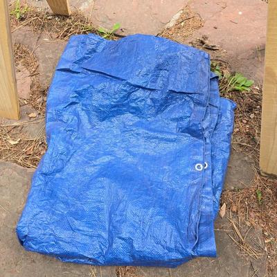 Wooden sawhorse, a blue tarp, Irwin clamp, and a trashcan