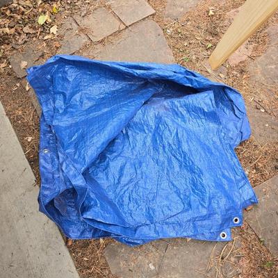 Wooden sawhorse, a blue tarp, Irwin clamp, and a trashcan