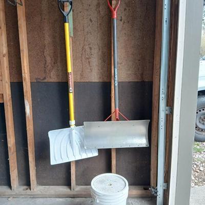 Two snow shovels - one metal - one plastic and a lidded bucket for ice melt