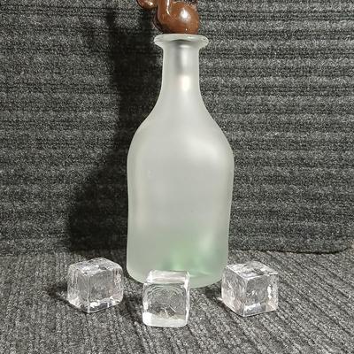 Empty Glass Frosted bottle with horse rear stopper and three glass ice cubes / clear glass cubes