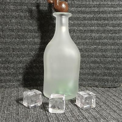 Empty Glass Frosted bottle with horse rear stopper and three glass ice cubes / clear glass cubes