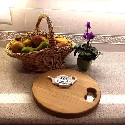 A BASKET OF REALISTIC FRUIT, CUTTING BOARD AND A FAUX FLOWER