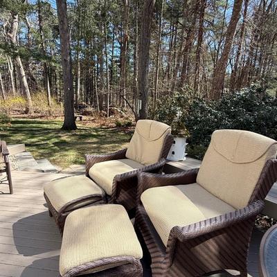 Two wicker chairs with cushions and foot stools