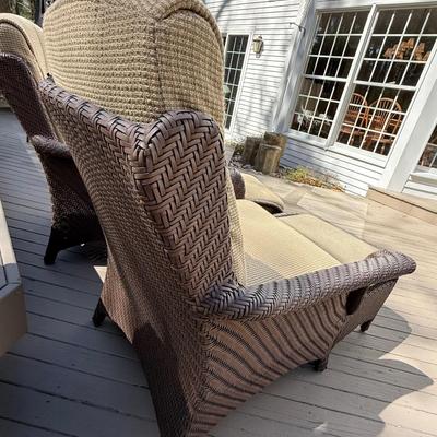 Two wicker chairs with cushions and foot stools