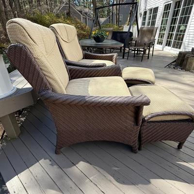 Two wicker chairs with cushions and foot stools