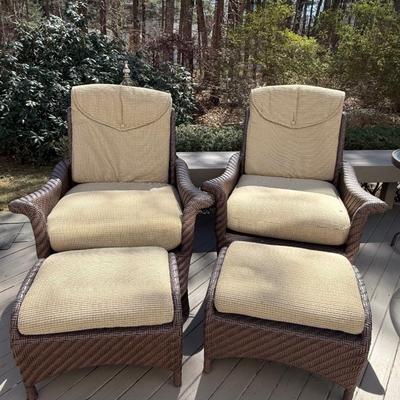 Two wicker chairs with cushions and foot stools
