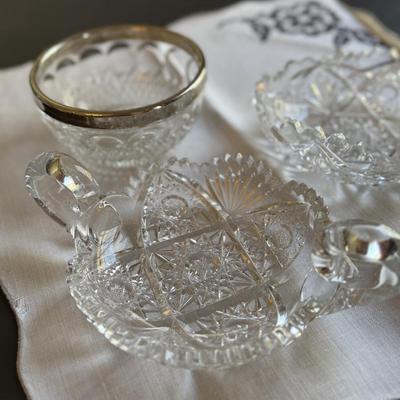 Two cut glass candy dishes with handles and silver rimmed bowl