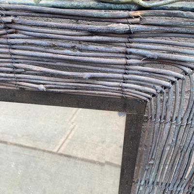 Rustic woven effect framed mirror with bird nest feature on frame.