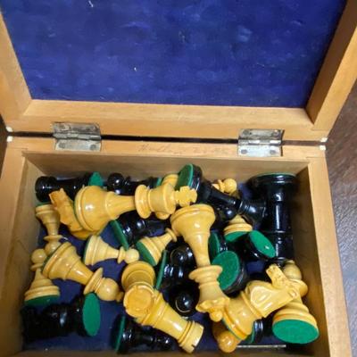 Wood carved bird and box filled with chess pieces