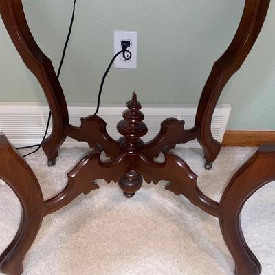 ANTIQUE PARLOR TABLE ON CASTERS AND A HEAVY CRYSTAL CUT LAMP