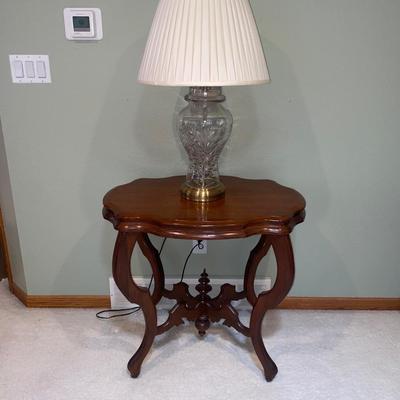 ANTIQUE PARLOR TABLE ON CASTERS AND A HEAVY CRYSTAL CUT LAMP