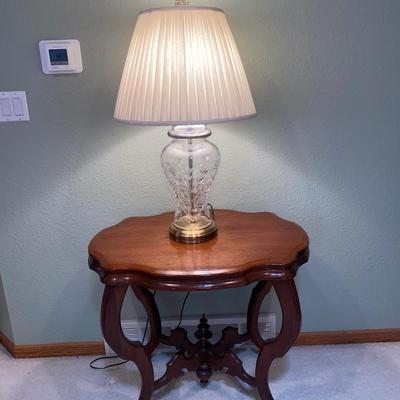 ANTIQUE PARLOR TABLE ON CASTERS AND A HEAVY CRYSTAL CUT LAMP