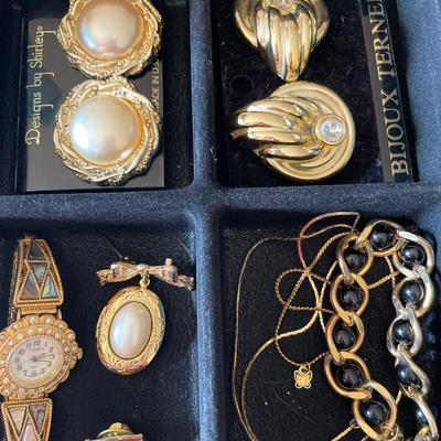 Black organizer of gold tone jewelry
