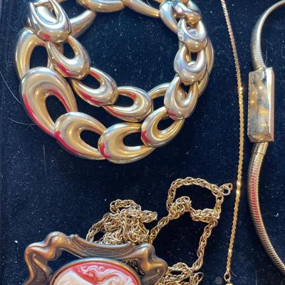 Black necklace holder with gold tone jewelry