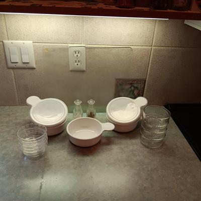 5 CORNING WARE DISHES WITH HANDLES, GLASS SHAKERS, RAMEKINS AND A GLASS CUTTING BOARD