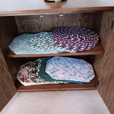 2 DOOR CABINET FILLED WITH PLACEMATS AND A LAMP WITH A DIMMER SWITCH