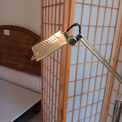 A ROOM SCREEN AND AN ADJUSTABLE BRASS COLORED FLOOR LAMP