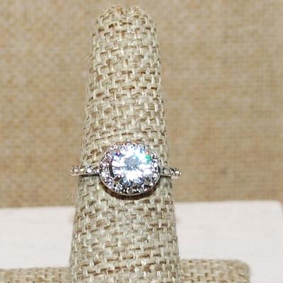 Size 6 Single Round Clear Main Stone with Side Accents & Set on a Circle Setting on a Silver Tone Band (2.6g)